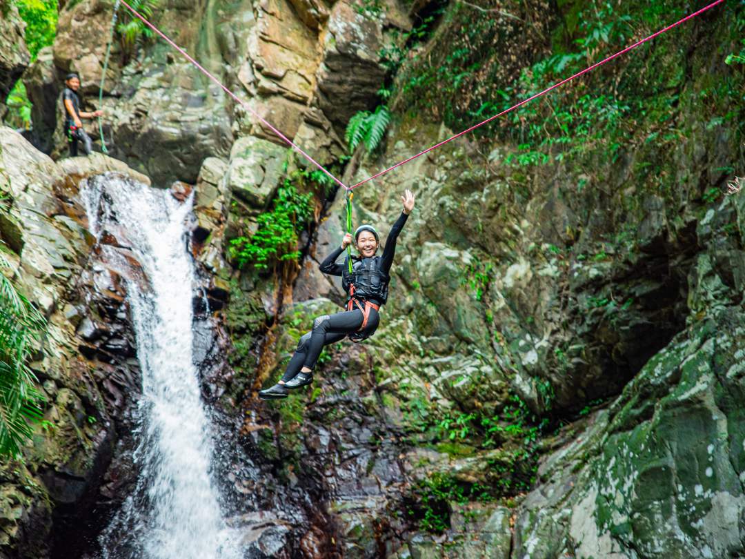 川を奥へ進むと、神秘的な雰囲気をまとう滝が現れます。この滝を舞台に、いよいよツアー最大の目玉「ジップスライド」に挑戦！安全を確保した上で、滝の上から一気に滑り降りる爽快感は格別です。